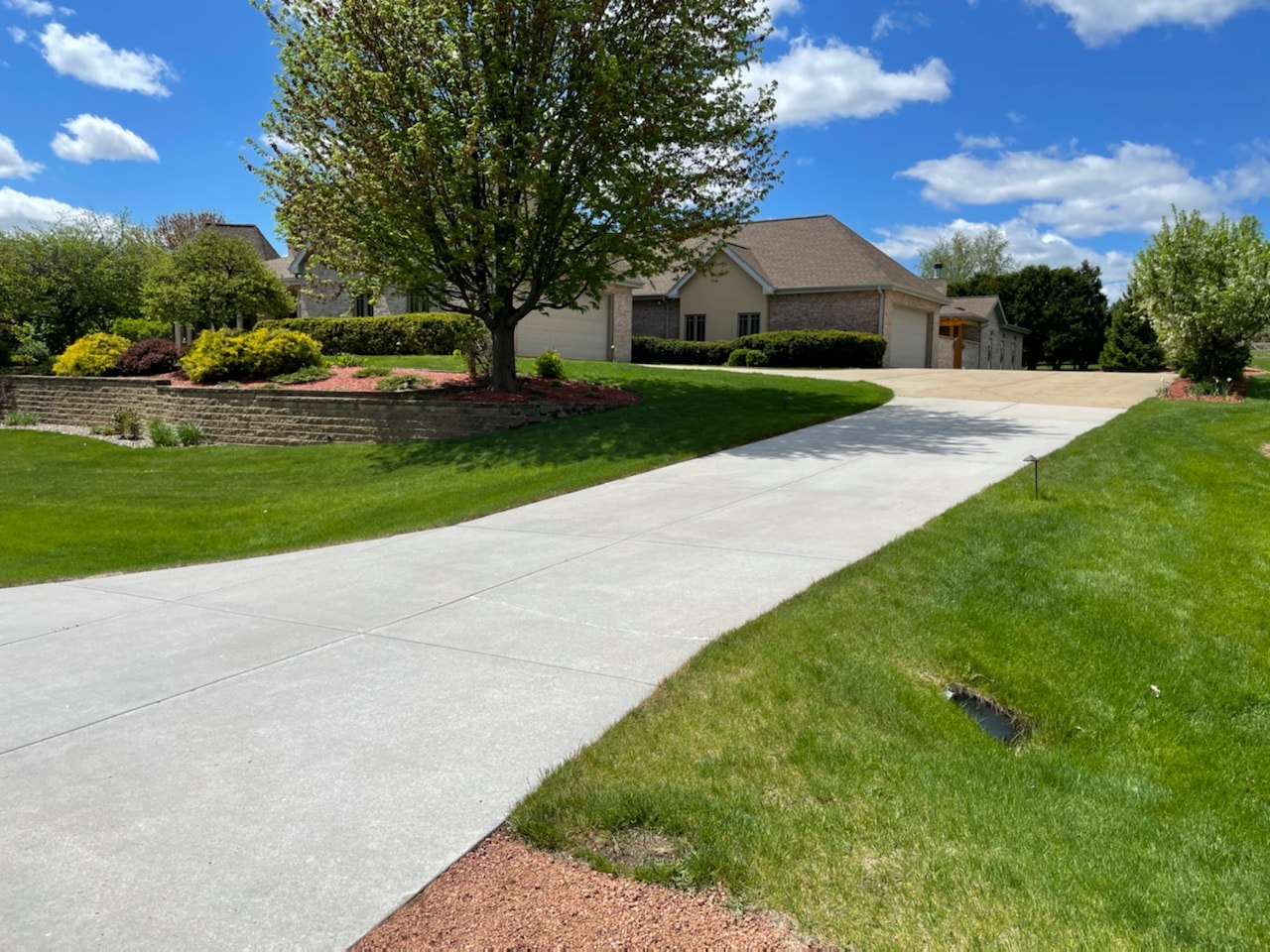 Concrete driveway — bottom half treated and bright white, top half untreated with rust staining — Expert Concrete Care